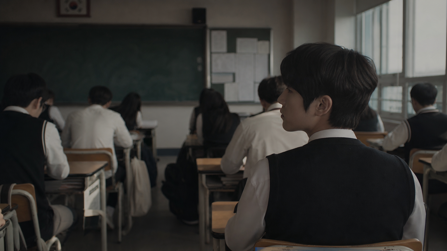고등학교 교실에서 뒷자리에 앉아 친구들을 관찰하는 소년