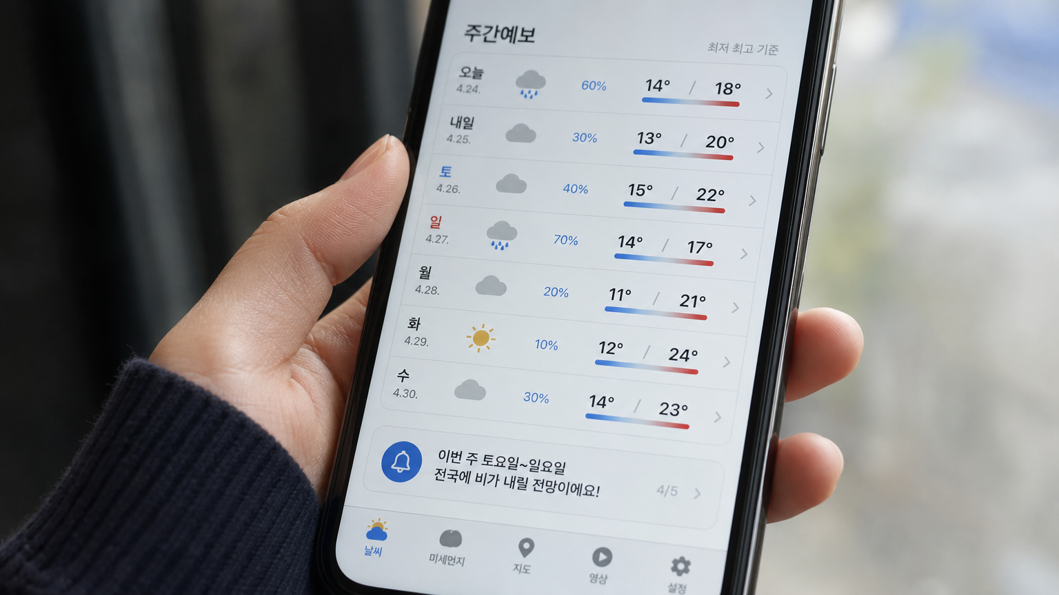 스마트폰으로 주간 날씨 예보 앱을 확인하는 모습