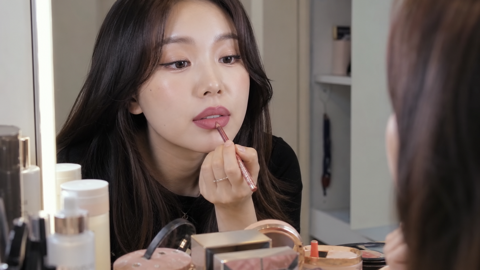 거울 앞에서 오버립 메이크업 기술을 사용하는 여성의 클로즈업