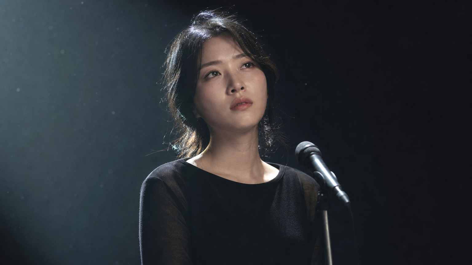어둡게 조명된 무대 위에서 감정을 표현하는 이은주 배우