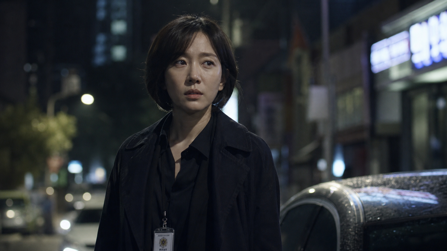밤 도심 거리에서 집중하는 표정으로 형사 역할을 맡은 한국 여배우의 모습