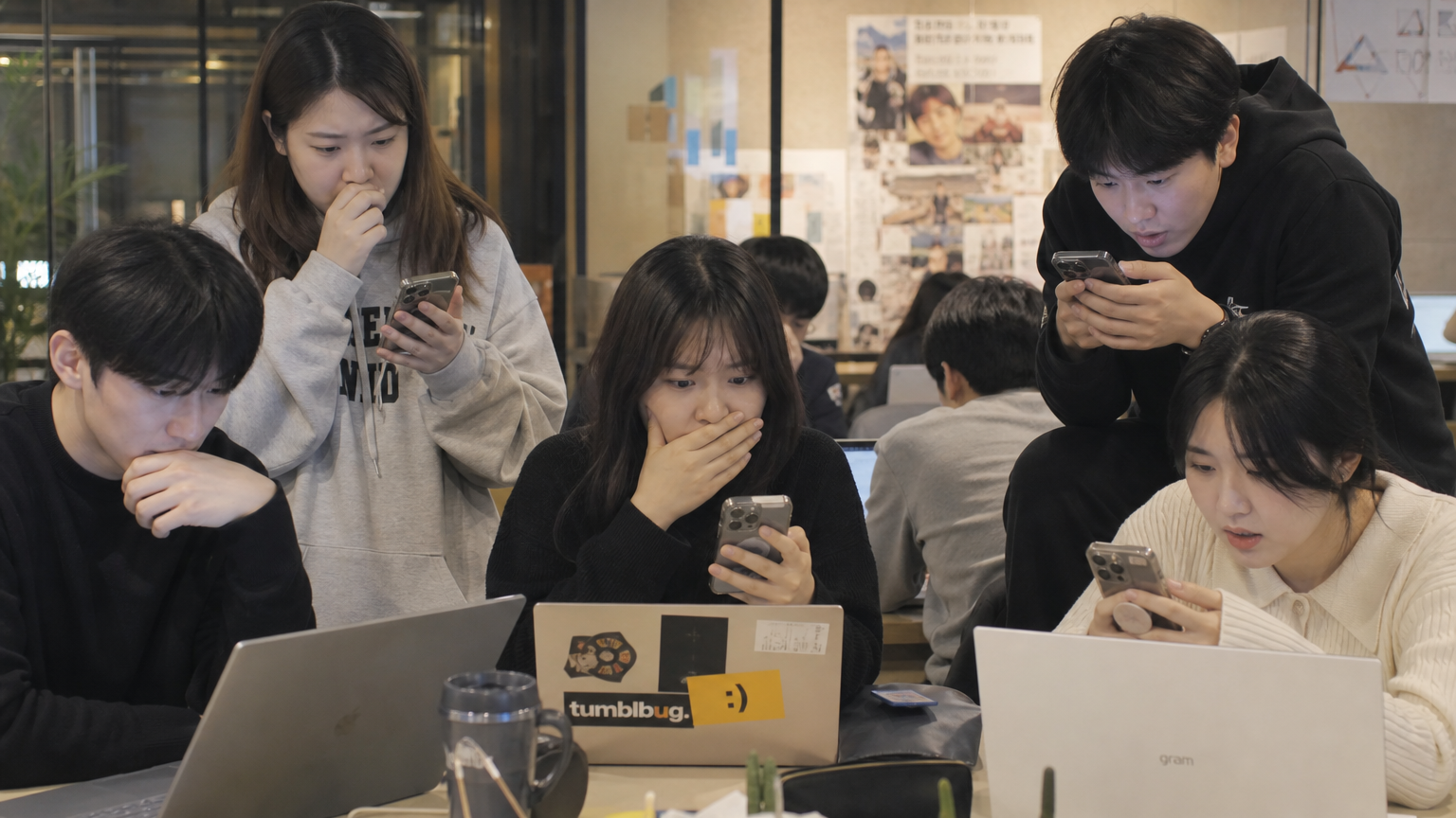 젊은 한국 사람들이 현대적인 공유 오피스에서 실시간으로 SNS를 통해 연예인 스캔들을 팔로우하는 장면