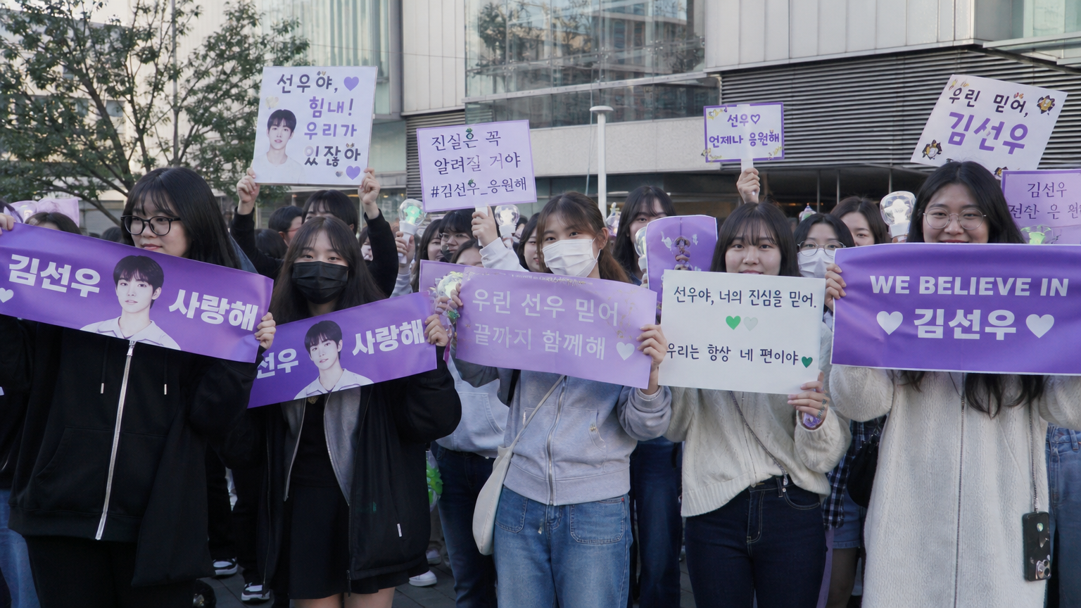 활기찬 도시 거리에서 좋아하는 아이돌을 응원하며 플래카드를 든 열정적인 팬들의 모습