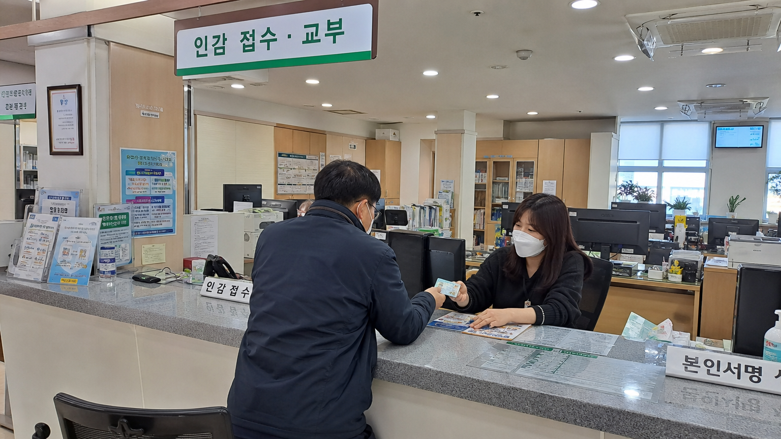 지역 주민센터에서 신분증을 보여주며 인감을 등록하는 성인들의 모습