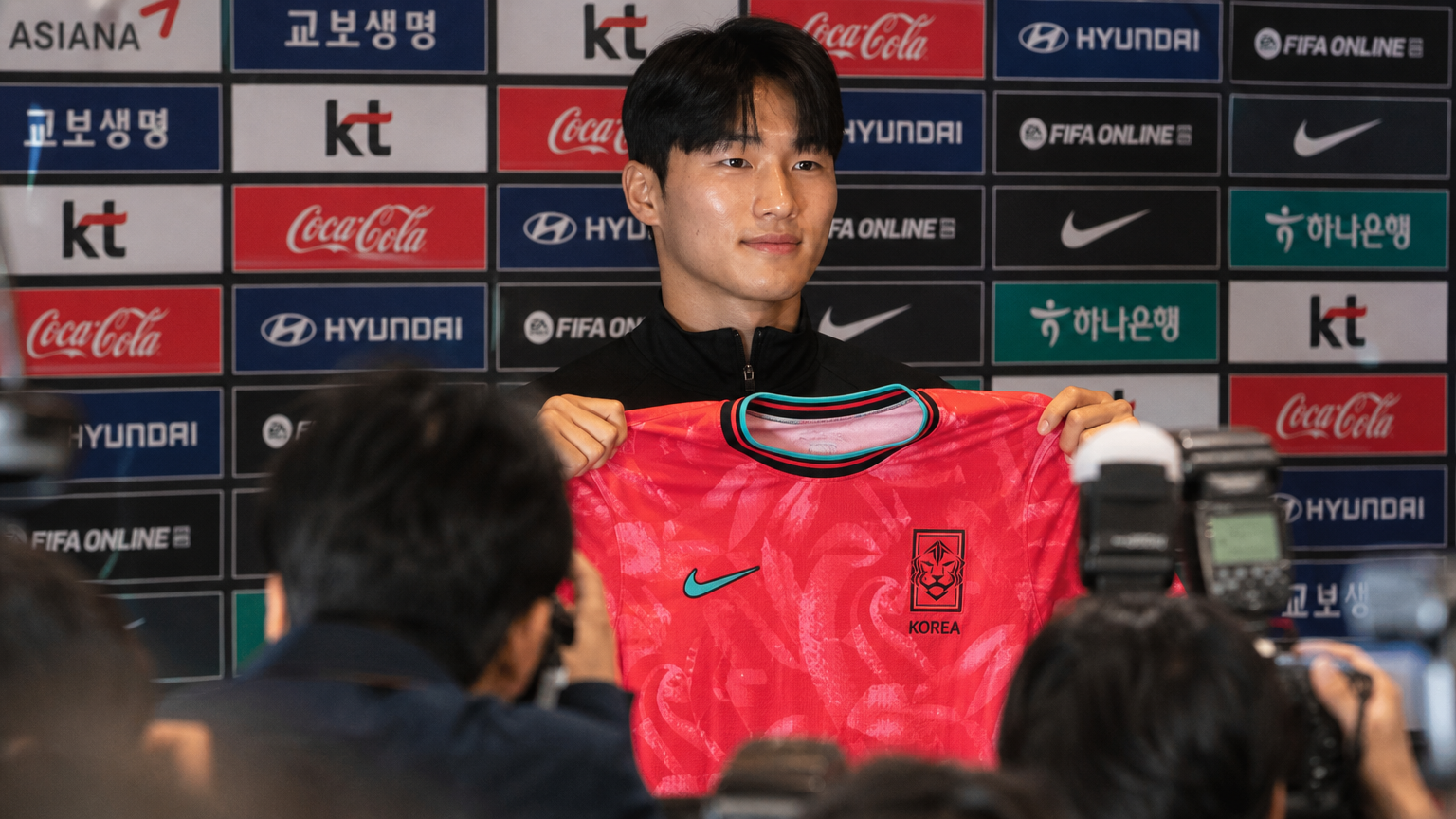 기자회견장에서 처음으로 한국 축구대표팀 유니폼을 들고 있는 젊은 선수