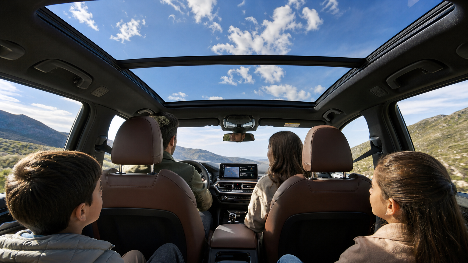 맑은 날씨 속에서 BMW X3 내부에서 보이는 넓은 유리 지붕과 주변 풍경을 즐기는 가족들