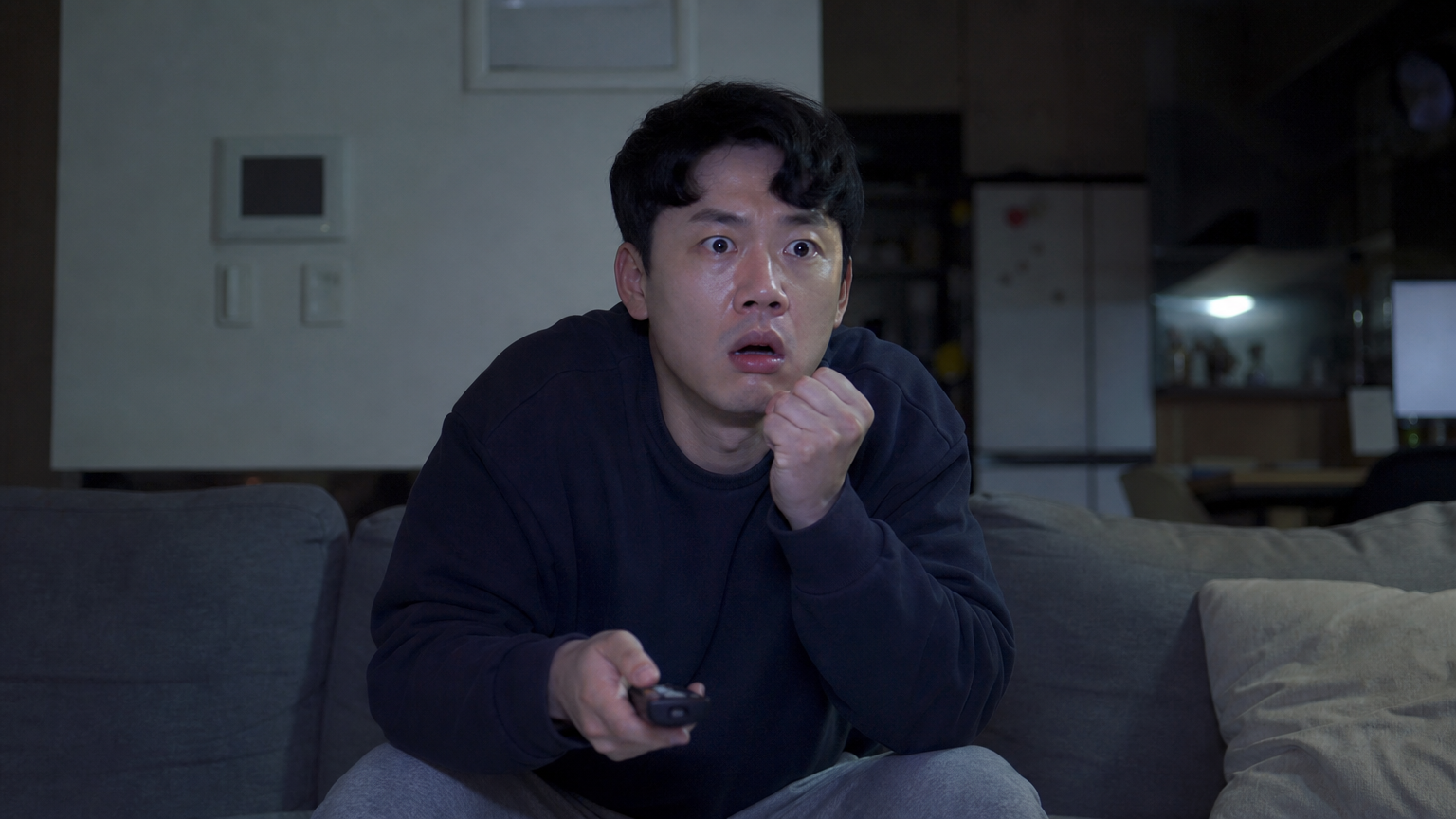 한국 남성이 TV를 보며 놀란 표정을 짓고 있는 모습