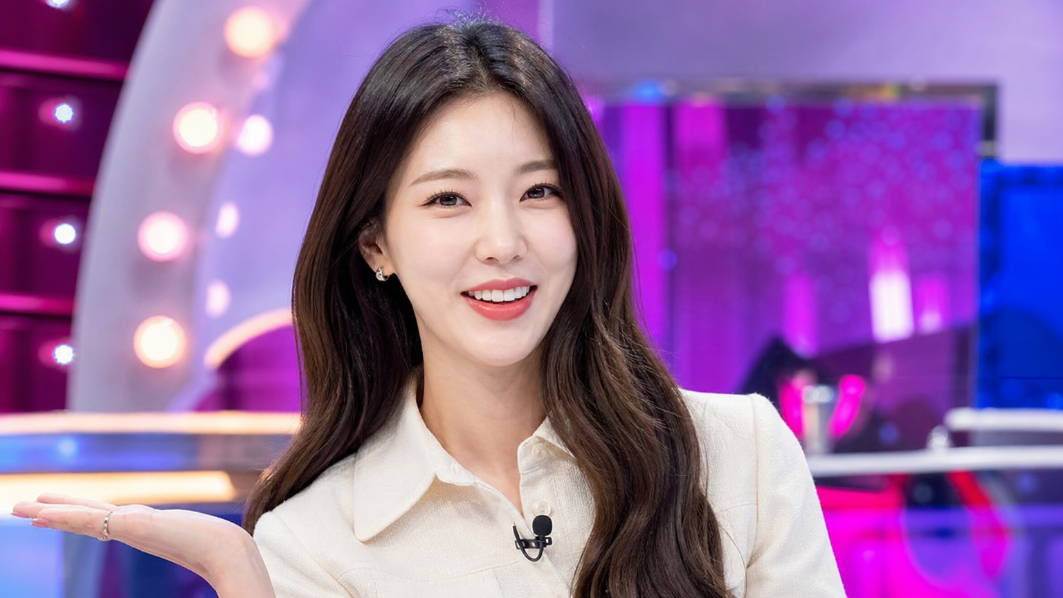 활기찬 에너지로 가득한 한국 여성 연예인이 밝은 조명 속에서 매력을 발산하는 장면