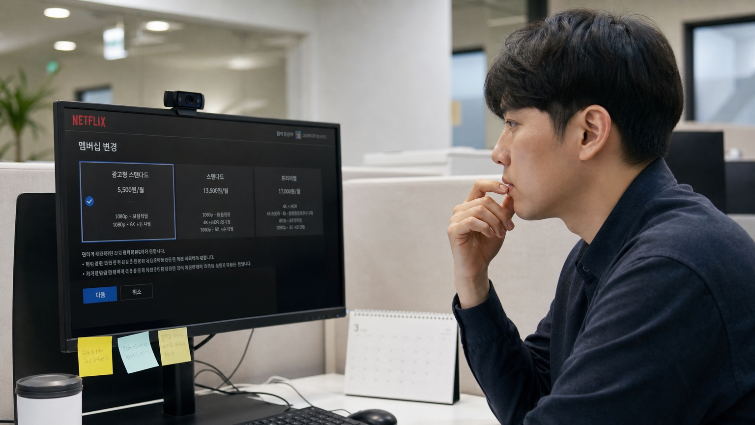 사무실 책상에 앉아 넷플릭스 구독 정보를 보며 고민하는 한국인 직장인의 모습