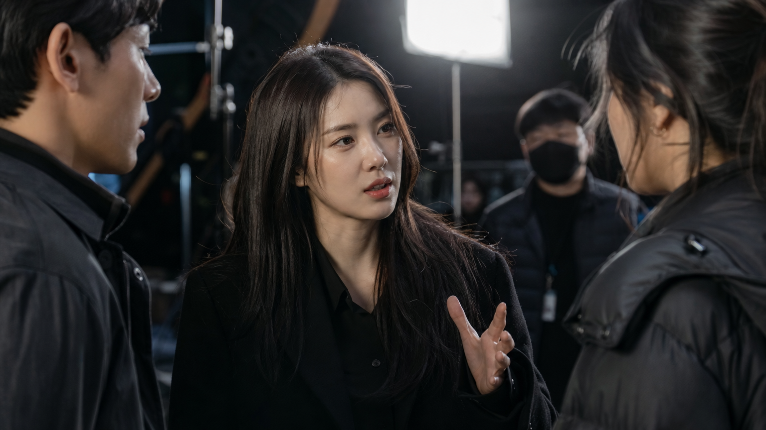 영화 세트장에서 동료 배우들과 진지하게 대화를 나누는 한국 여배우
